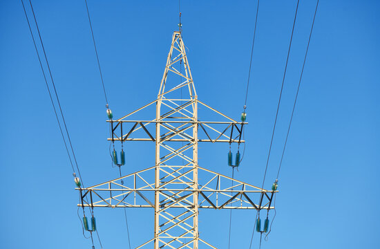High voltage electricity tower with power line against blue sky. Overhead electric power line with insulators. Electricity generation, transmission, and distribution network. Indastry landscape.