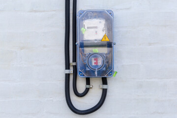 Domestic digital electricity meter in transparent case, mounted on wall