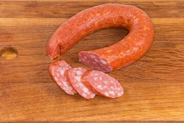 Partly sliced boiled-smoked sausage on a wooden cutting board