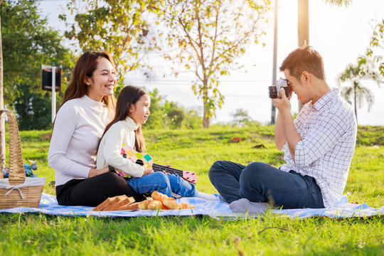 Happy family picnic. A little girl takes a picture of her parents) during picnicking on a sunny day
