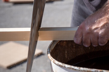 A man cutting a piece of wood with a hand saw.