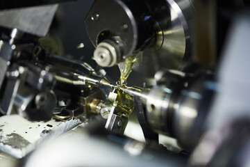 Close-up of CNC machine producing detail with usage of lubricant pouring on metal