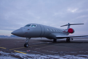 Private jet parked at the airport with engine plugs on against a cloudy sky