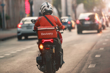 A food delivery driver is driving deliveries to customers ordering food online in a busy capital...