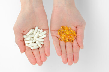 A woman holds antidepressants or vitamins in her hands. White and yellow pills in female palms, top...
