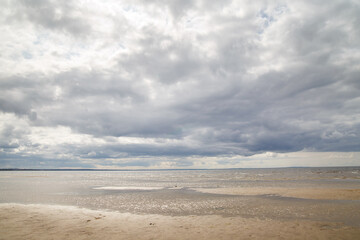 Landscape with sandy beach of the Gulf of Finland with low clouds.