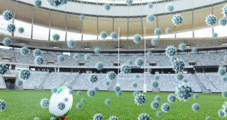 Multiple covid-19 cells floating against rugby ball on sports stadium