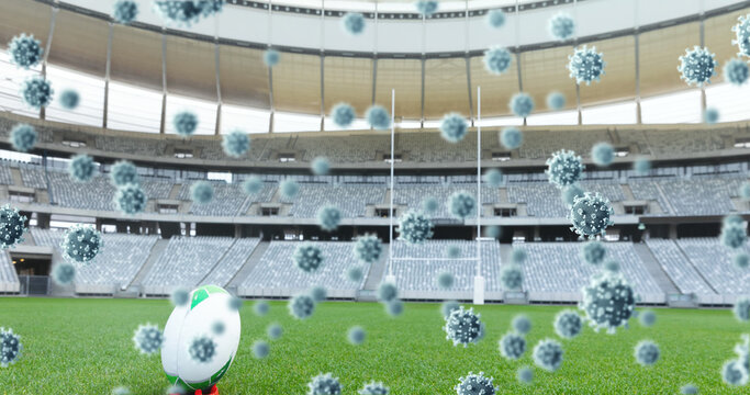Multiple covid-19 cells floating against rugby ball on sports stadium