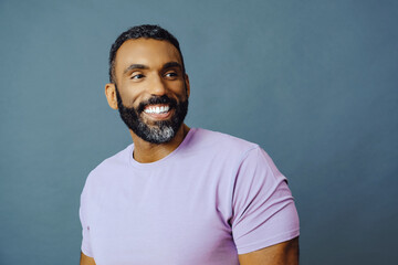 headshot of a handsome smiling african american man with beard and mustache purple shirt on a gray...