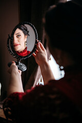 Portrait of beautiful woman in red vintage 1800s early 1900s clothing with mirror.