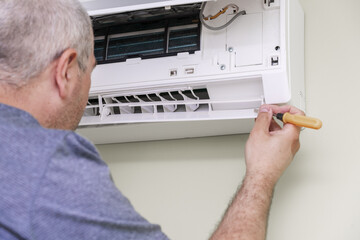 man using screwdriver to repairing air conditioner