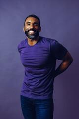 portrait of a handsome smiling man with beard and mustache purple shirt on a gray looking at camera...