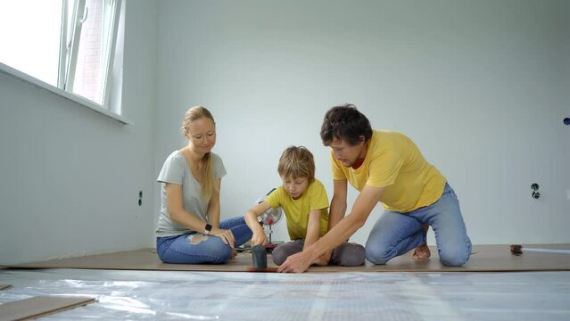 A family of mother, father and son install laminate on the floor in their apartment. DIY concept