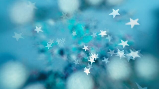 Bokeh effect white stars on a blue background in motion. Dynamic background in cold winter style. Christmas toys are blurred. Motivation of mood with a New Year's background.