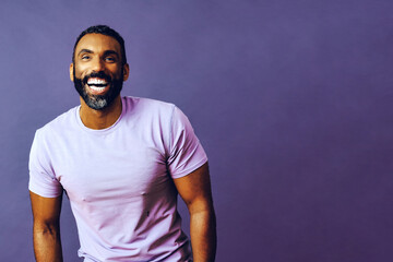 Fototapeta portrait of a handsome smiling man with beard and mustache purple shirt on a gray looking away at copy space background studio obraz