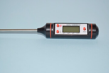 Food digital thermometer with probe on blue background.