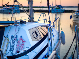 view on moored sailing yacht hull and rigging on a pier, dawn waterscape view