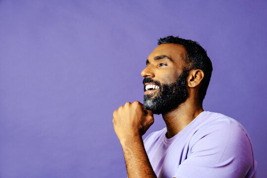 profile headshot of a handsome smiling african american man with beard and mustache purple shirt looking away at copy space studio