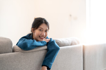 Teenager Asian woman feeling happy smiling and looking to camera while relax in living room at home.