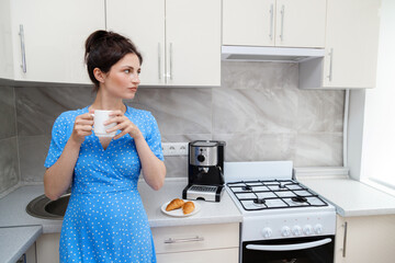 woman in the morning in the kitchen with coffee near the coffee machine