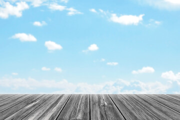 Old gray wood table with blue sky and white clouds. Empty plank desk with blurred beautiful blue sky background.