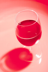 Glass of wine with dark shadow. Wine glass in red monochrome.