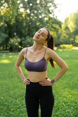 a girl outdoors in the park goes in for sports in a sports purple top in black leggings on a blue sports mat in the background a meadow and trees