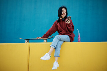 Beautiful Chinese woman with skateboard. Portrait of urban young girl outdoors.