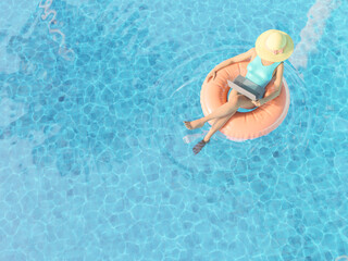woman with laptop floating in pool in swim ring