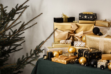 Preparations for the holiday, for dressing the Christmas tree, black and gold gifts and Christmas toys and decorations on the table near the fir tree