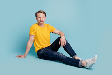 Cheerful handsome guy sit floor enjoy break rest wear casual clothes isolated on turquoise background