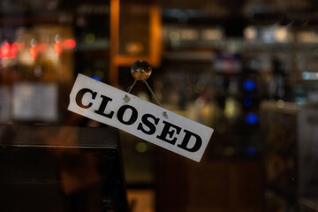 Closed Sign on glass shop door with background lights