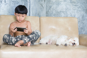 Boy using mobile phone relaxing at home. Puddle dog is a friend to stay beside. 