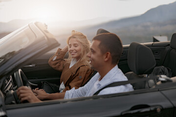 Close up of happy couple man and woman traveling driving a convertible car, side view. Trip concept