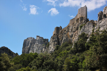 Fototapeta na wymiar Mountain forest with the ruins of the medieval Peyrepertuse Castle on steep rocks in Duilhac, Occitanie region in France