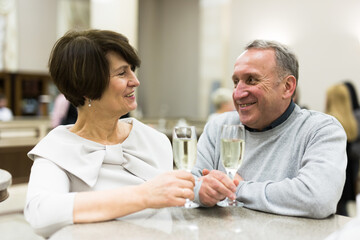 Mature man and woman drinking champagne in theater lobby