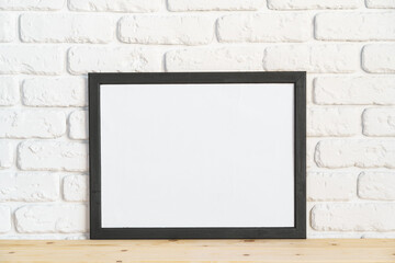 Photo frames on floor over white brick wall