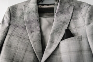 A man's jacket, grey suit on a hanger in the room. Close up.