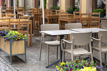 Fototapeta na wymiar Empty table in outdoor cafe or restaurant. Tables and chairs at sidewalk cafe. Touristic setting, cafe table, sidewalk cafe furniture.