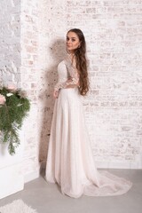Bride in a white dress against a brick wall.
