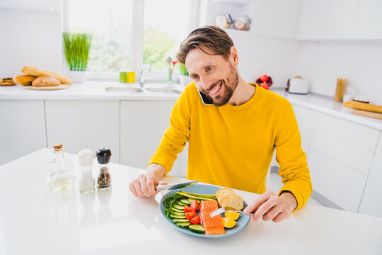 Photo of young man speak listen communication mobile phone eat fish steak meal dinner fresh dieting indoors