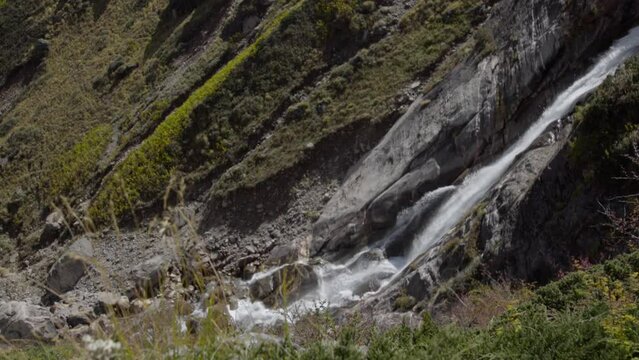Natural Waterfall in the Himalayas, Garhwal Himalayan range, near Kedarnath Temple in Uttarakhand, India. Falling water hitting water surface, some huge rocks. Lush green leaf.