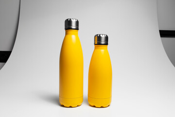 Close-up of two yellow reusable water bottles on white studio background.