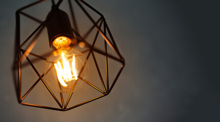 Close-up of hanging lamp glowing with warm light on dark background. Good idea.
