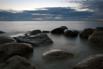 Scenic view of the sea after sunset with rocks and stones