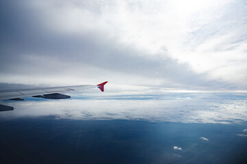Fototapeta na wymiar Aircraft wing above beautiful clouds and blue sky