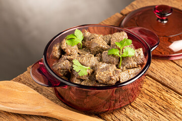 Stewed meat in the pan on the wooden table. Meat stew.
