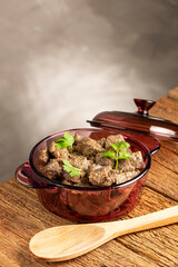 Stewed meat in the pan on the wooden table. Meat stew.