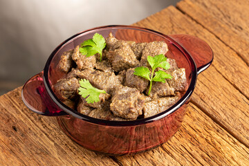 Stewed meat in the pan on the wooden table. Meat stew.