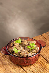 Stewed meat in the pan on the wooden table. Meat stew.